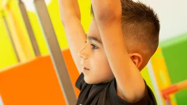 A Five Pea gymnast reaching overhead in a preschool gymnastics class at Cal Elite