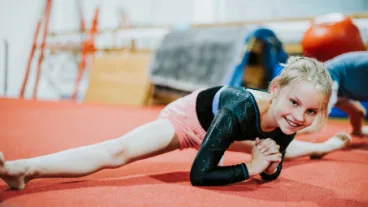 A Level 3 recreational gymnast holding a split on the floor at Cal Elite