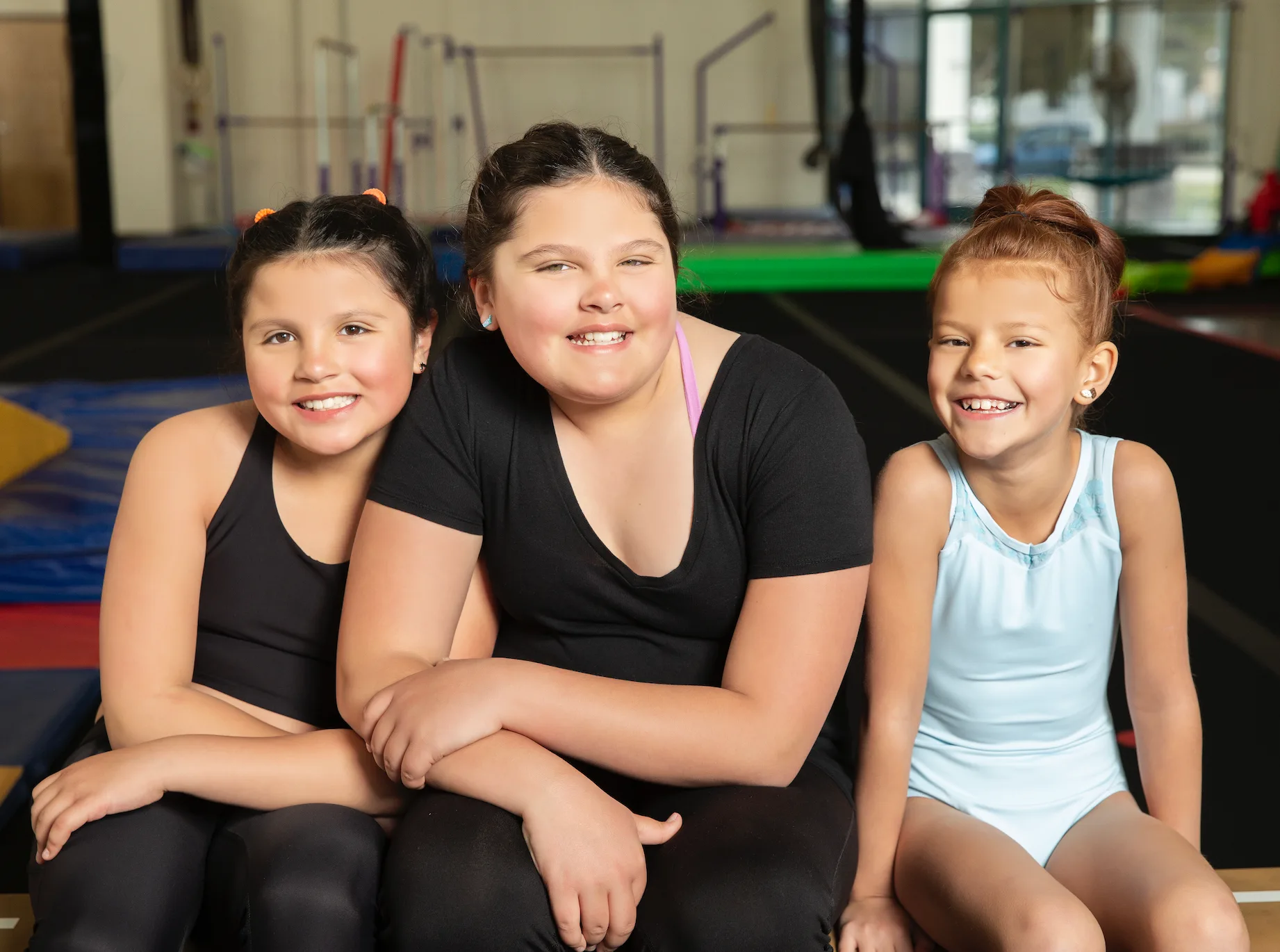 Three Cal Elite gymnasts smiling together after practice